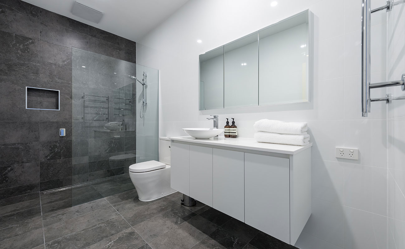 Modern tiled bathroom renovation with vanity, glass shower, white wall tiles and charcoal floor tiles